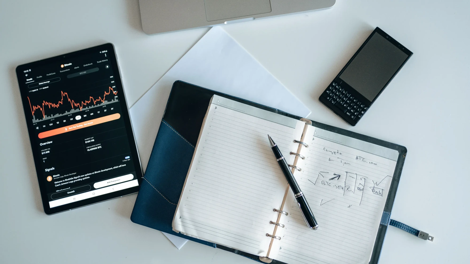 Skrivebord med laptop, notesbog med mødenotater og nøgletal på en tablet